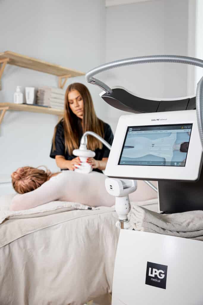Estetiker som använder en professionell LPG endermologie-maskin för en Forma kroppen med LPG-behandling på en klient i ett hälsocenter.