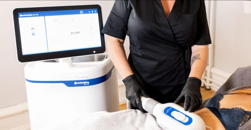 Sjukvårdspersonal som använder en kryolipolysmaskin för icke-invasiv fettminskningsbehandling på en patient.