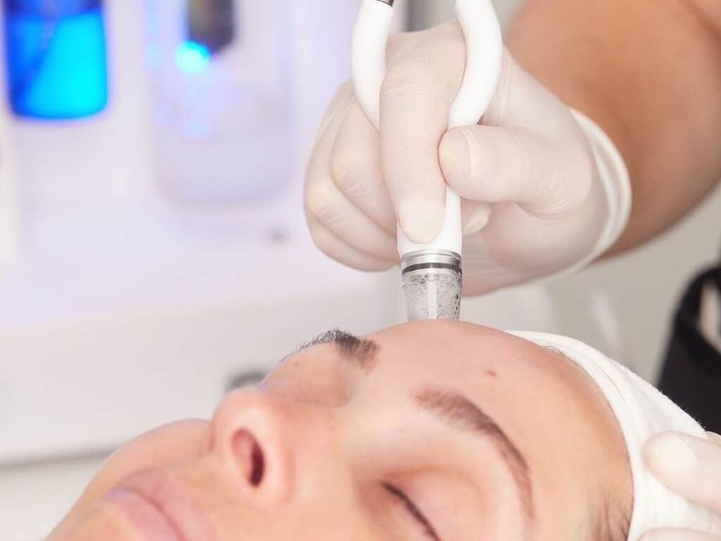 En person som får en ansiktsbehandling med en mikrodermabrasionsanordning på en hudvårdsklinik.