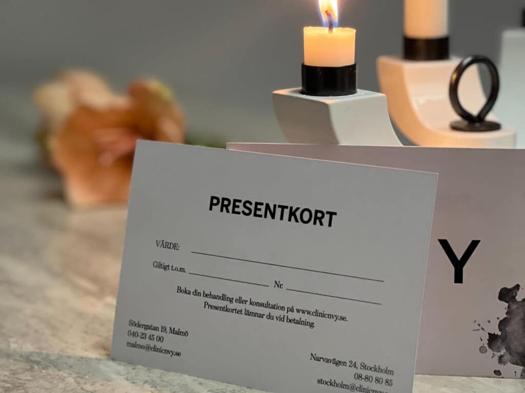 Ett presentkort på ett bord med ett tänt ljus i bakgrunden.